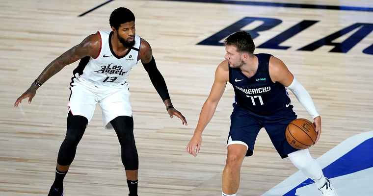 A Mavericks player attempts to dribble past a Clippers player