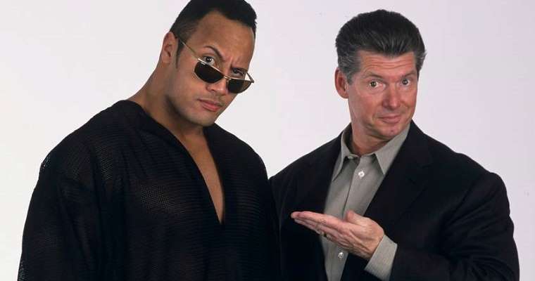 the Rock standing to the left of Vince McMahon