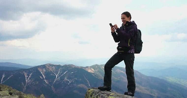 woman gambling on cell phone on a mountaintop