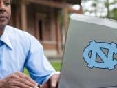 a person using a laptop to bet on sports with a North Carolina Tarheels sticker on it