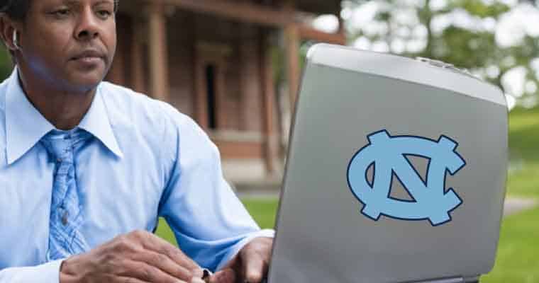 a person using a laptop to bet on sports with a North Carolina Tarheels sticker on it