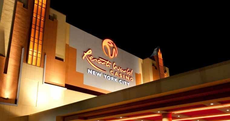 Night view of the Sports World Casino exterior with an illuminated sign reading 'Sports World Casino New York City' and warm orange lighting.